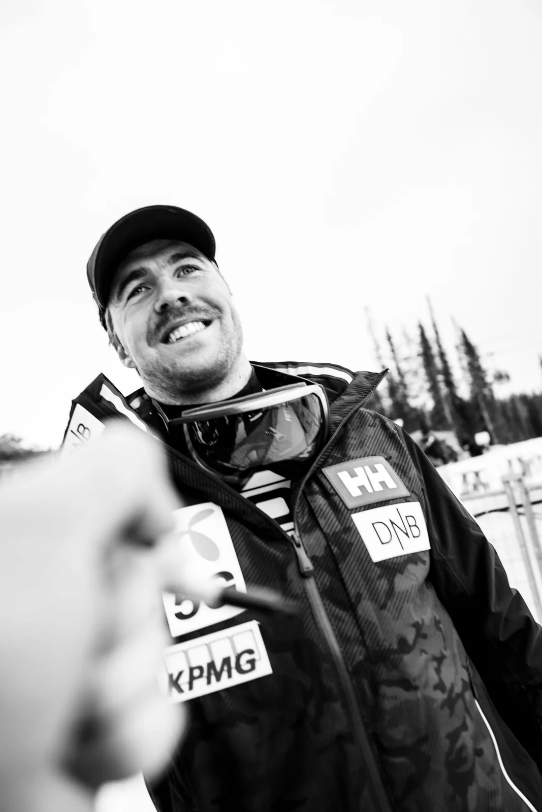 Black-and-white portrait of a ski racer smiling while signing autographs at the World Cup in Lake Louise