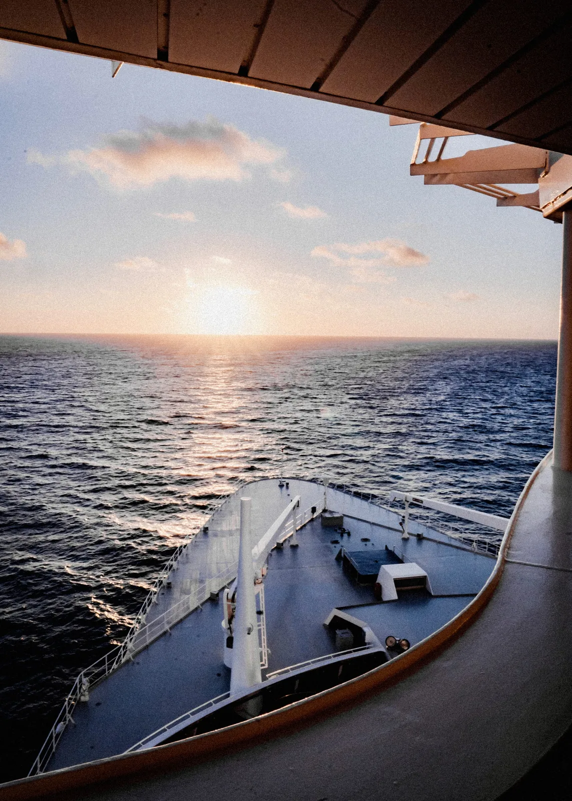 The bow of Queen Mary 2 at sunset, seen from high above as the ship heads west into the light